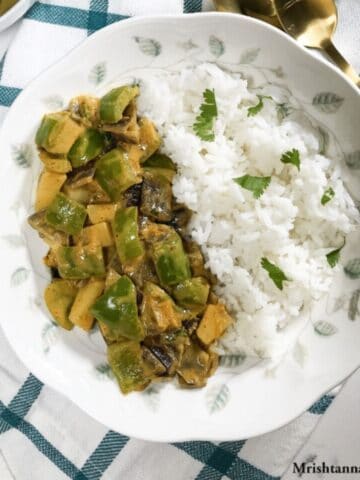 A plate is with potato capsicum curry and white rice.