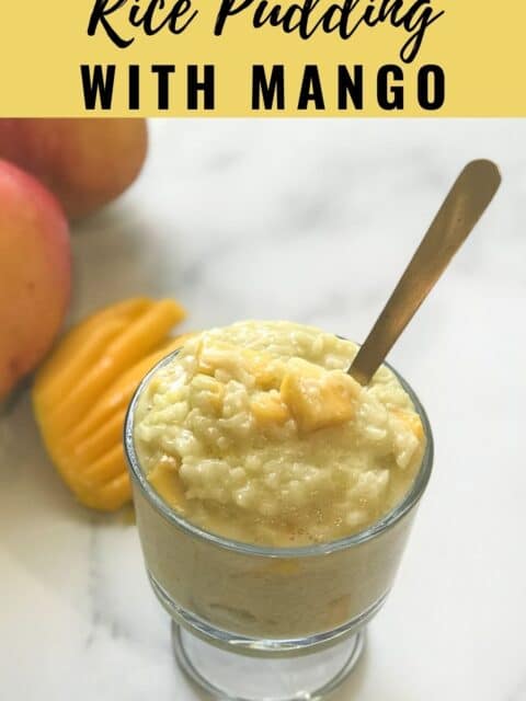 A glass bowl with mango rice pudding is on the table and spoon inserted