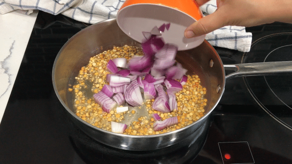 A pan on the stovetop with oil and onions