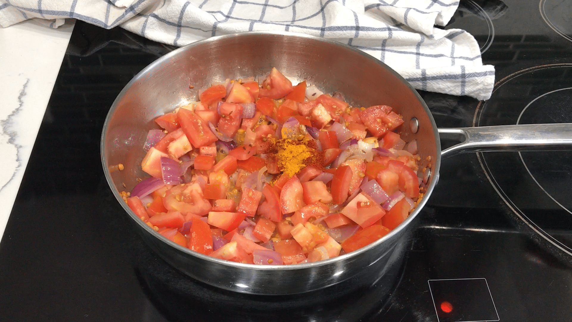 A bowl of food on a metal pan on a stove, with Chutney and Tomato