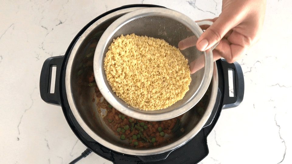 A person holding a pan of food, with millet 