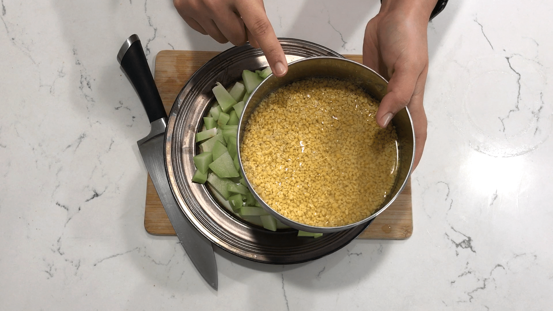 A person holding a bowl of food, with Dal and Chayote