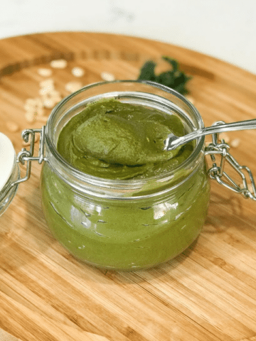 A jar of sauce sitting on top of a wooden table, with Pesto