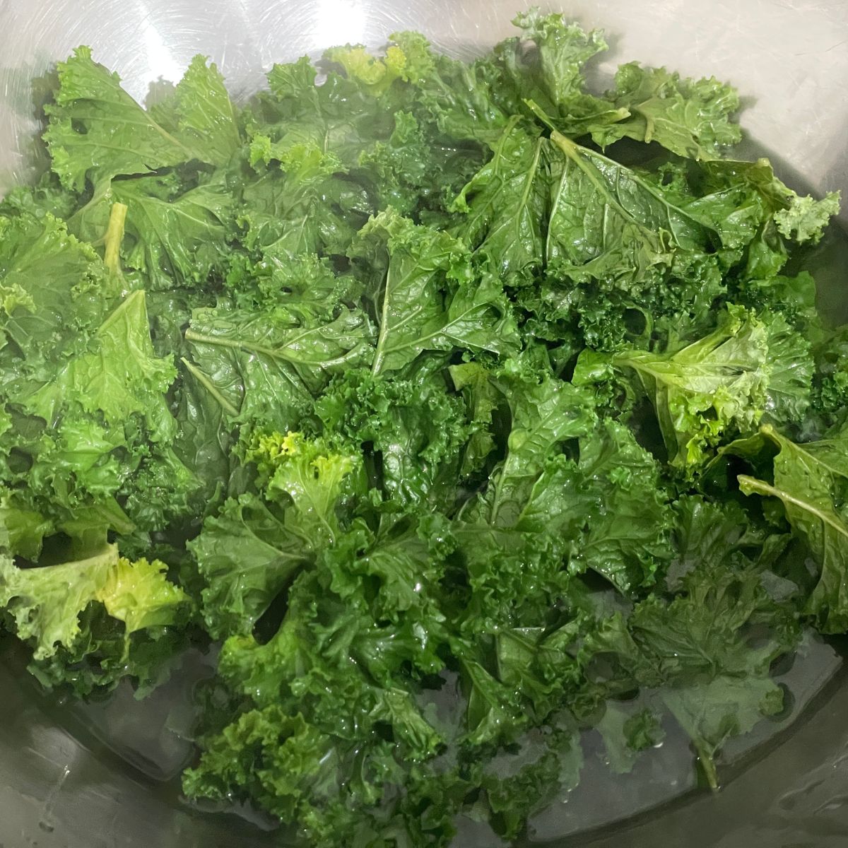 A bowl is with hot water and kale leaves.