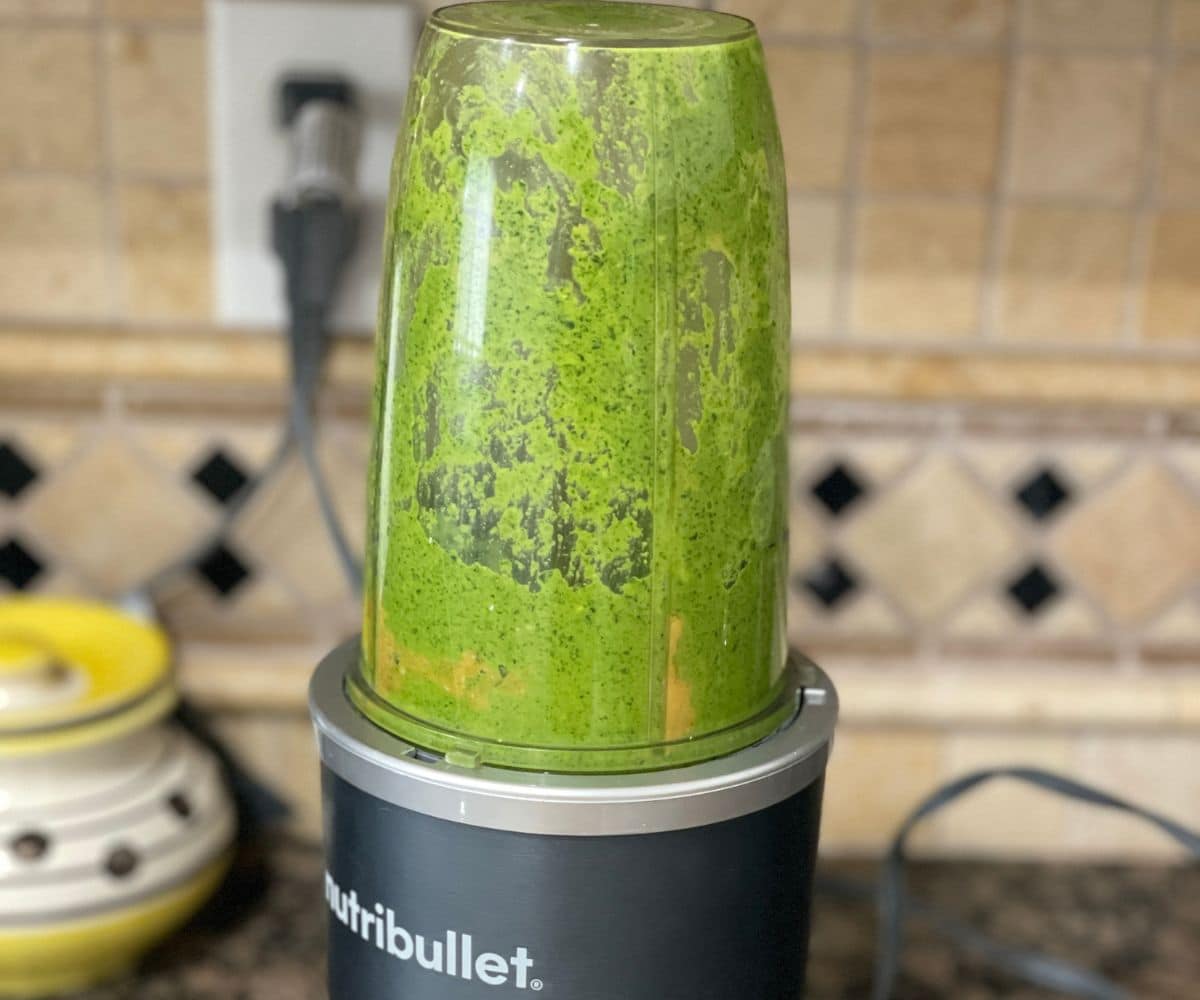 Kale cashew pesto is blending in a blender.