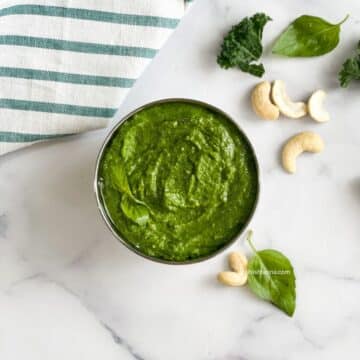A bowl of kale cashew pesto is on the surface.