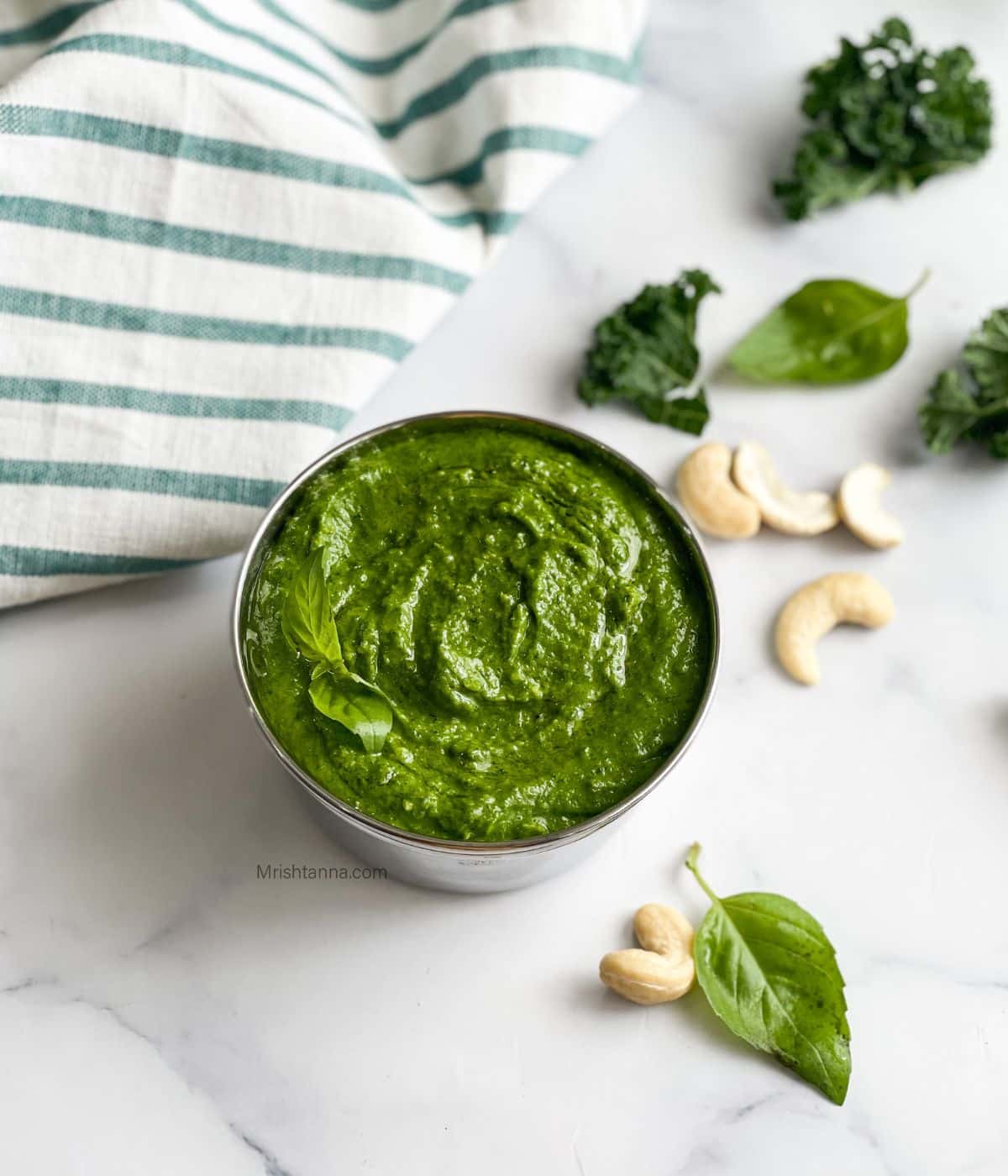 A bowl of kale cashew pesto is on the table.