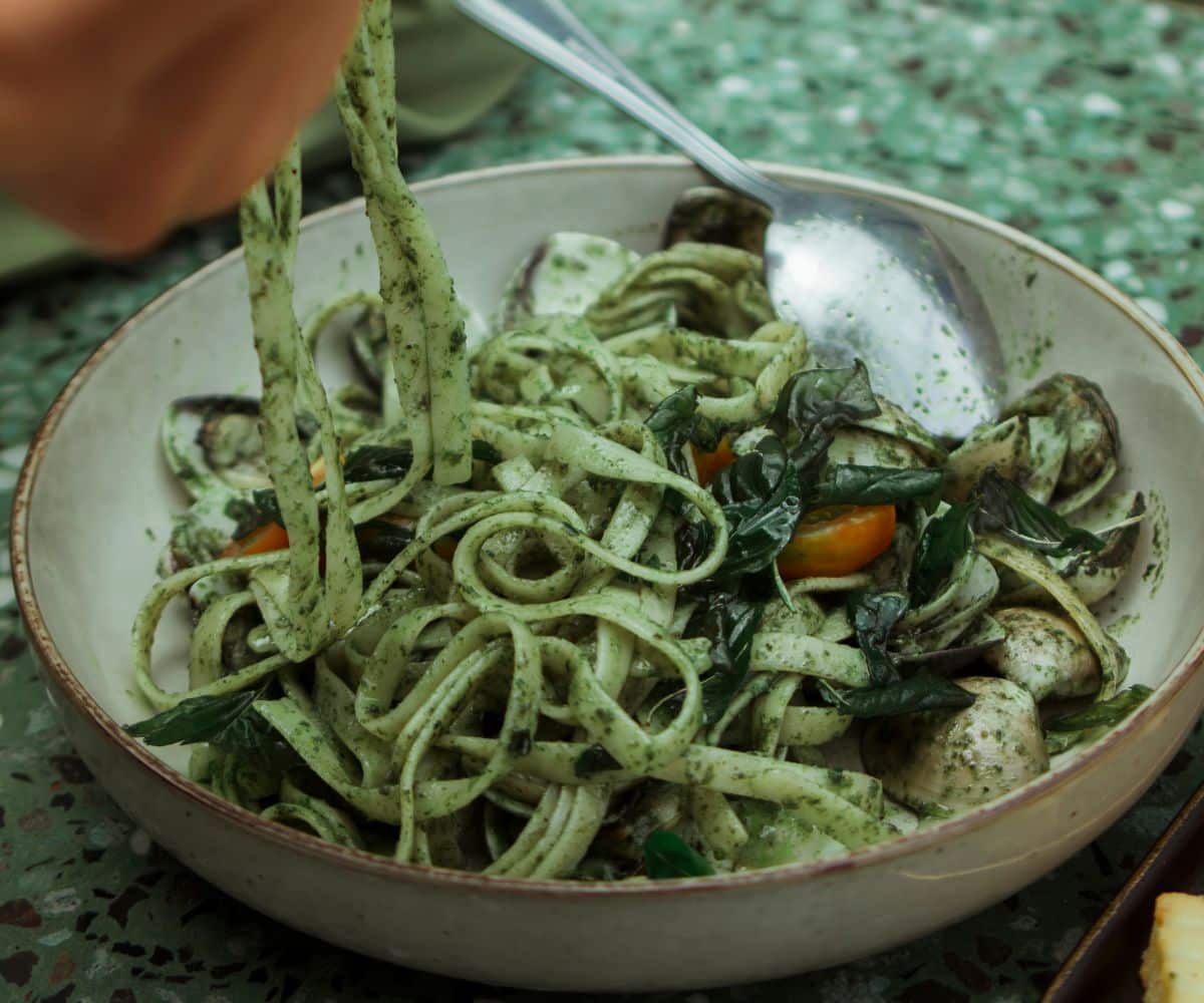 A bowl of pesto pasta is on the counter top.