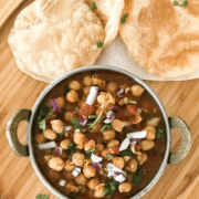A bowl of food sitting on top of a wooden table, with Chana masala