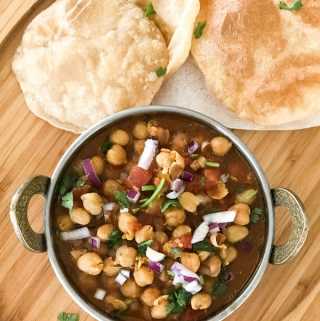 A bowl of food sitting on top of a wooden table, with Chana masala