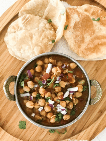A bowl of food sitting on top of a wooden table, with Chana masala