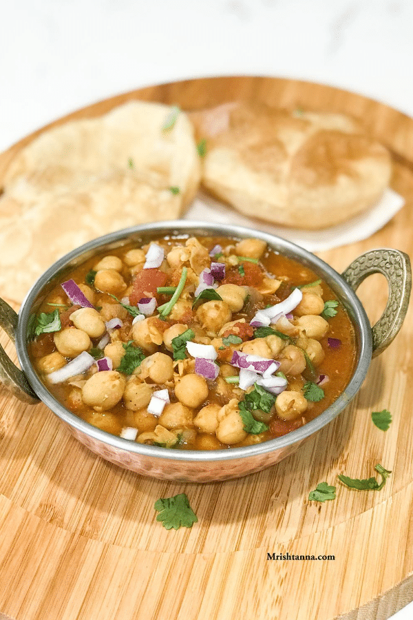 A bowl of food on a table, with Chana masala and Spice