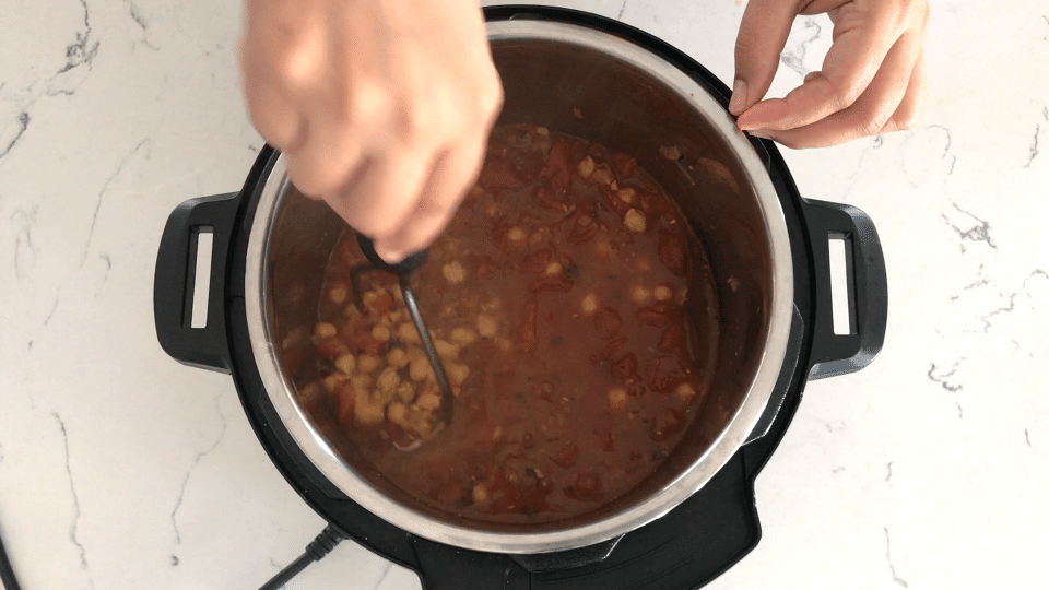 A close up of a pan on a stove, with Chana masala and Gravy