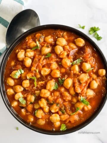 Vegan chana masala is in the bowl topped with cilantro.