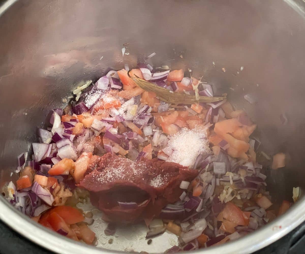 An instant pot is with tomato onions for chana masala.