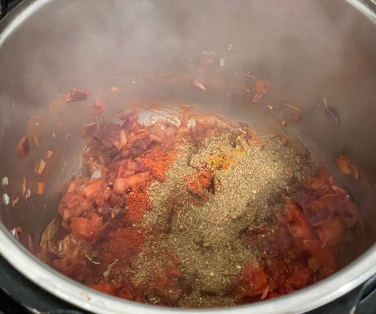 An instant pot is with spices and masala for chana curry.