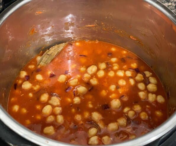 An instant pot is with chickpeas and masala.