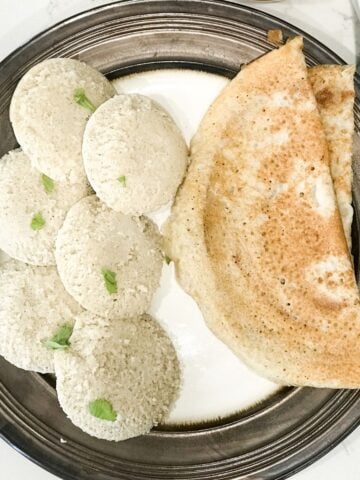 Millet idli placed on big plate with, dosa