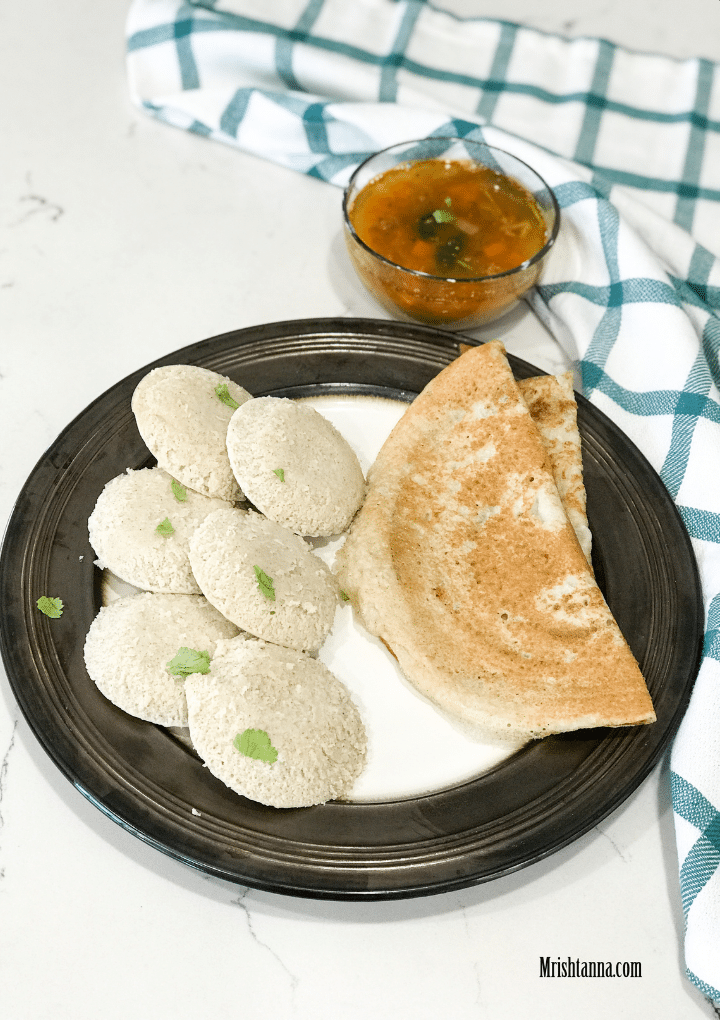 A plate filled with idlis and Millet dosa, along with bowl of sambar