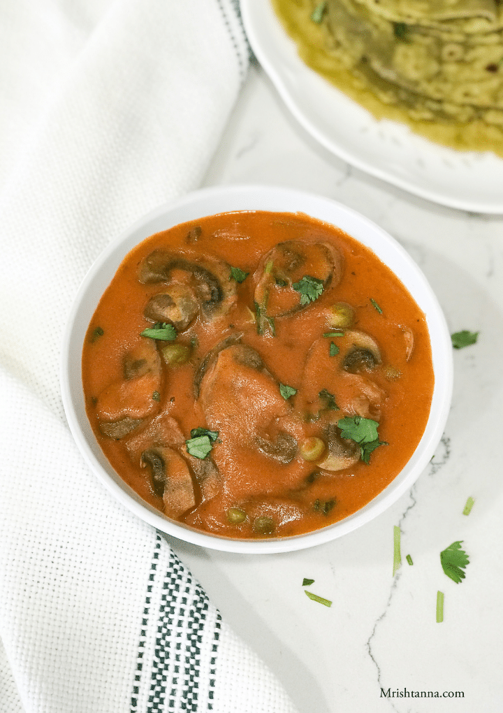 A bowl of mushroom curry on the white table