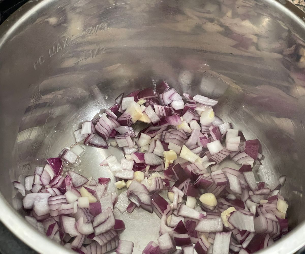 An instant pot is with onions and garlic on saute mode.