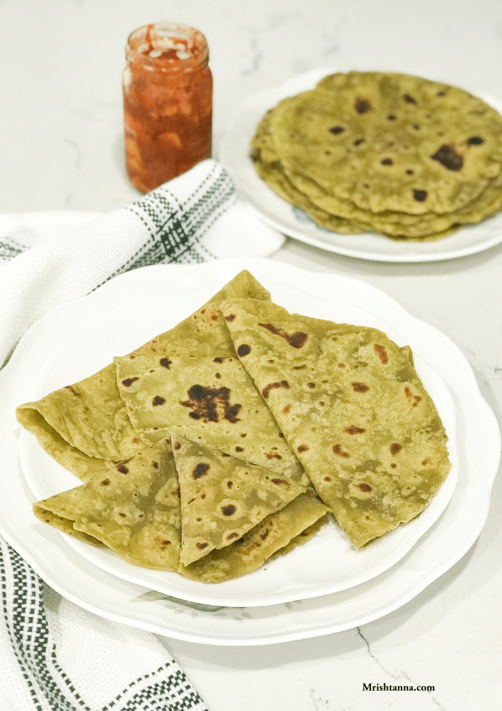 A white plate filled with avocado parathas along with pickle