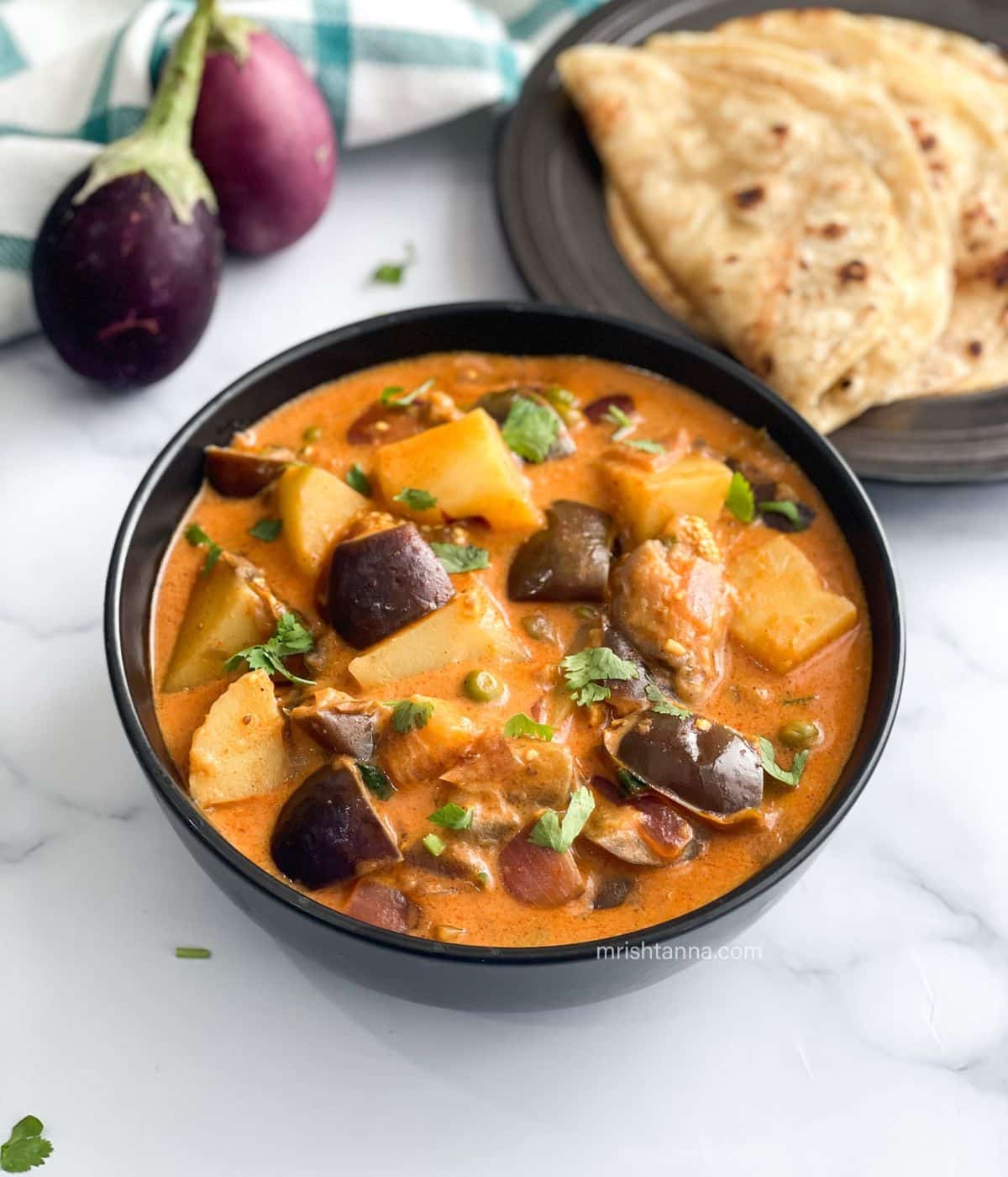 a bowl of eggplant curry is on the table.