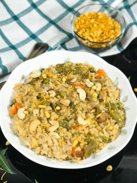 A plate is filled with bisi bele bath and topped with cashews