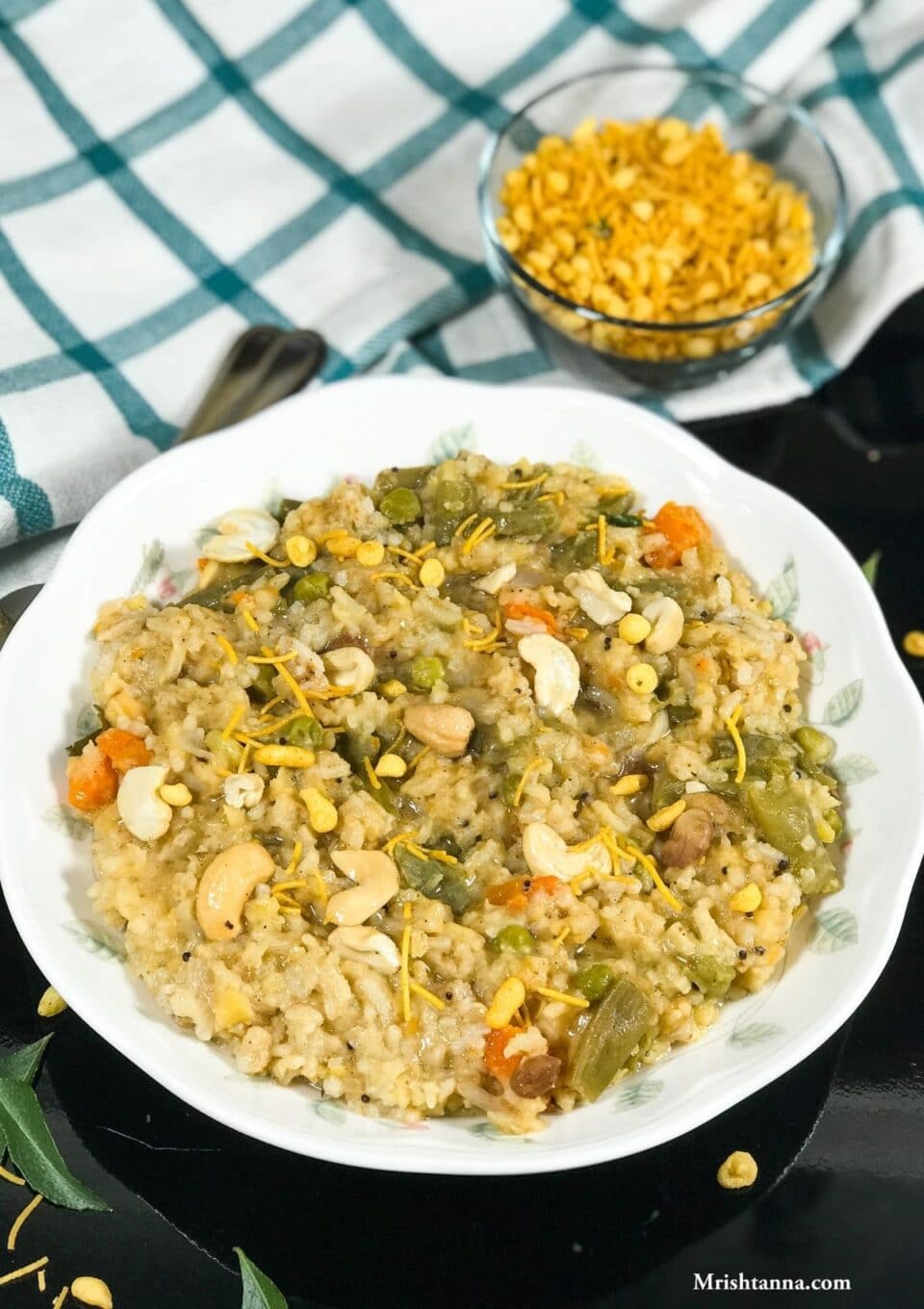 A plate is filled with bisi bele bath and topped with cashews