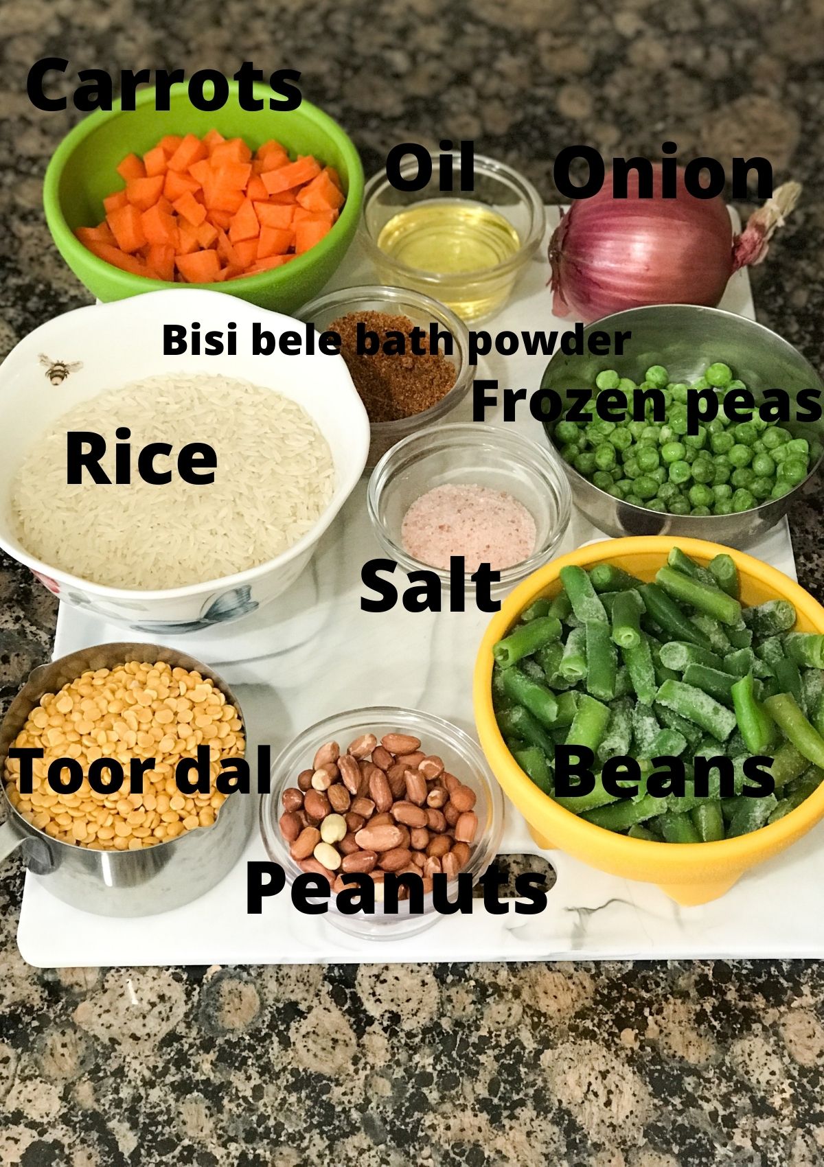 All the ingredients for bisi bele bath are placed on the counter including rice, dal, vegetables and oil