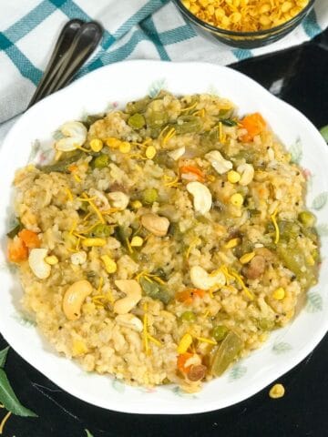 A plate of bisi bele bath is on the black serving tray
