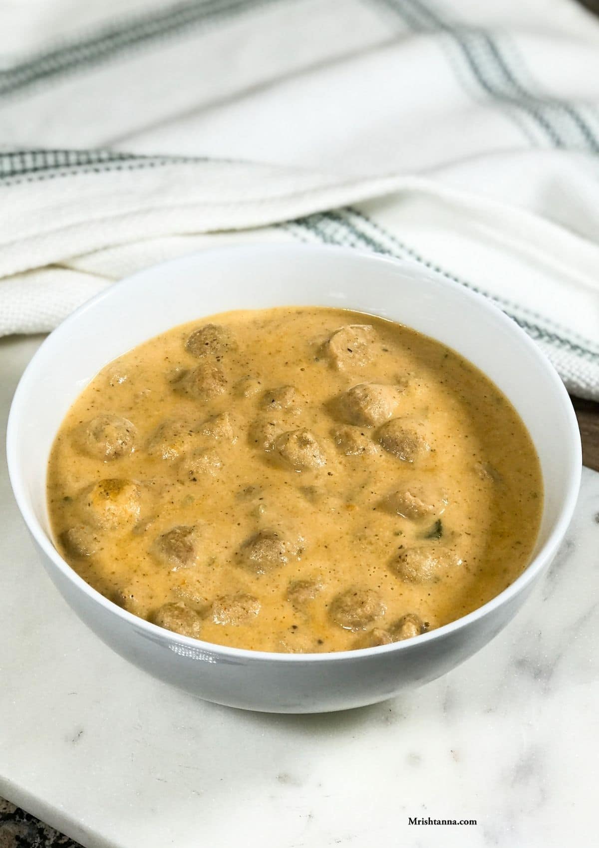 A bowl of meal maker curry is on the white serving tray