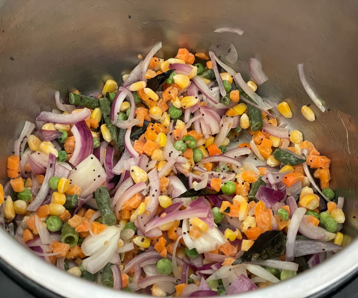 An instant pot has mixed vegetables and spices.