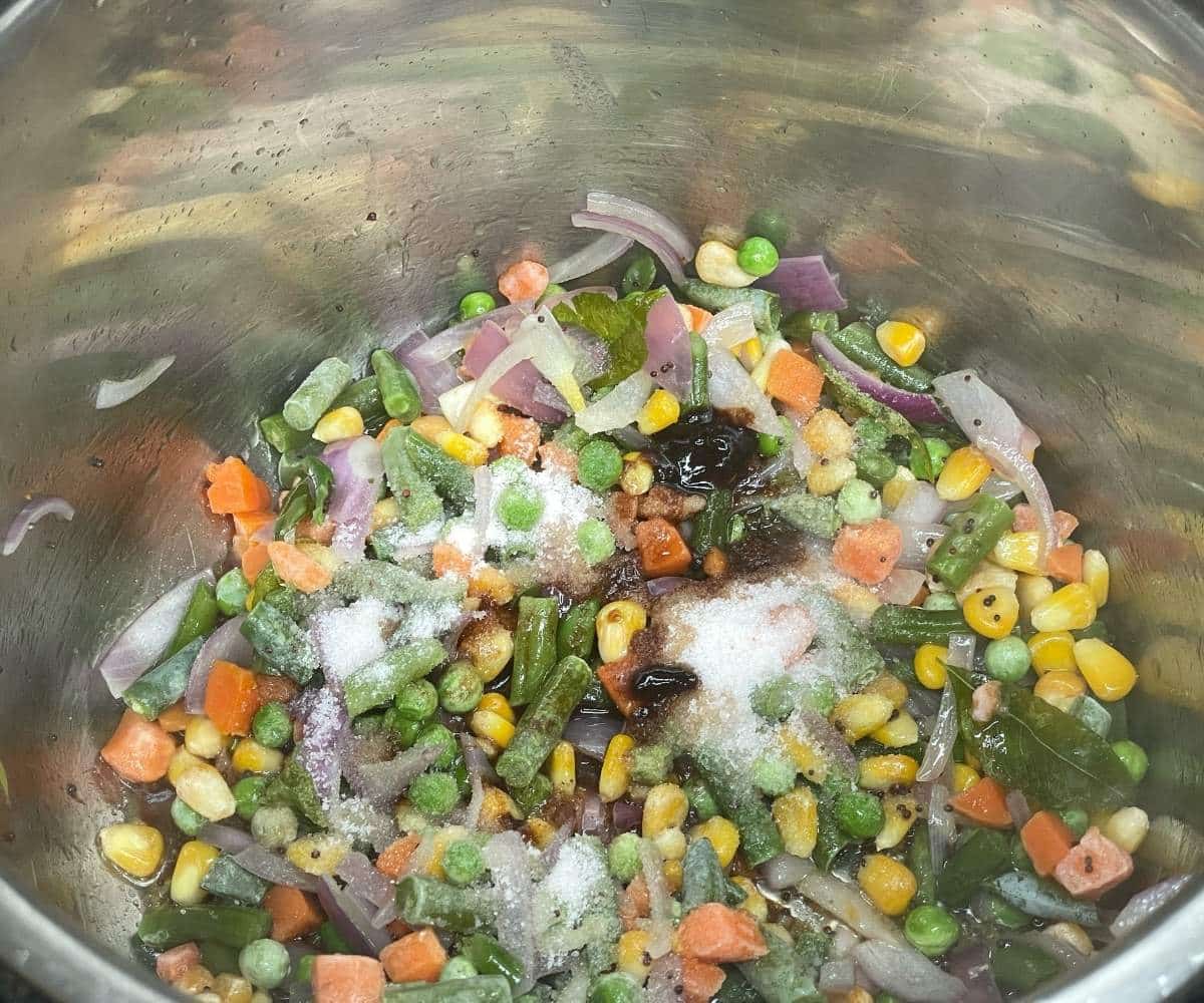 Instant pot has vegetables and onions to cook Bisi Bele bath recipe.