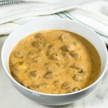 A bowl of kurma is placed on the white serving tray