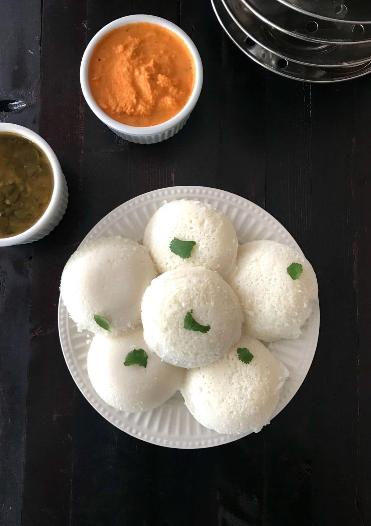 A plate with idli and cup of chutney