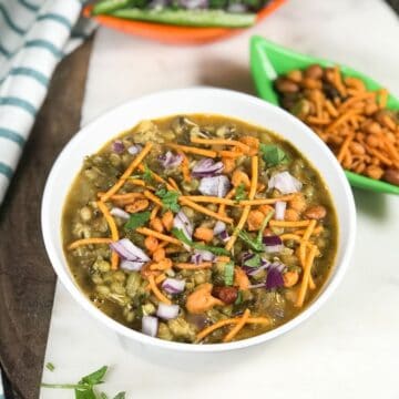 A bowl with misal masala and topped with red chopped onions