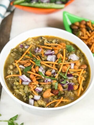 A bowl with misal masala and topped with red chopped onions