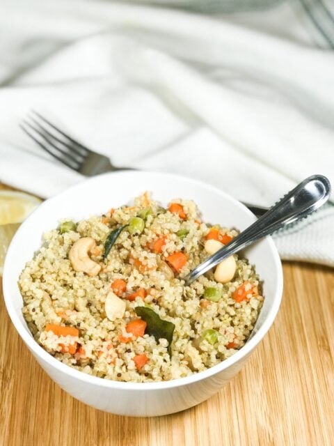 A bowl of quinoa upma with spoon inserted