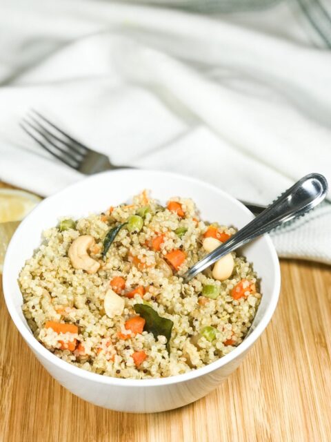 A bowl of quinoa upma with spoon inserted