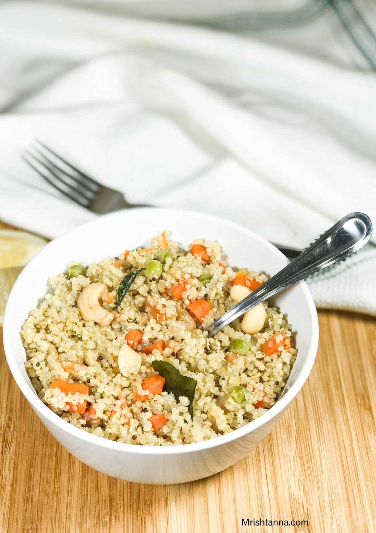 A bowl of quinoa upma with spoon inserted