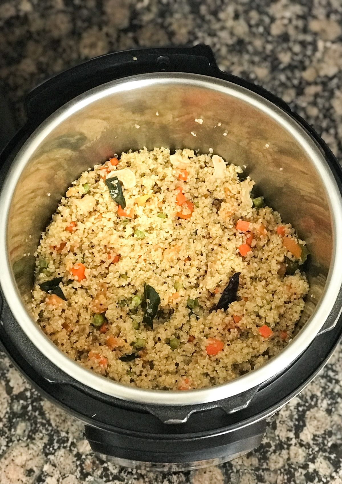 An instant pot with quinoa upma and topped with nuts