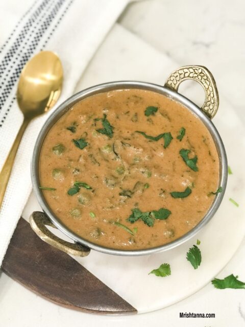 A bowl is filled with methi matar malai vegan curry and topped with cilantro