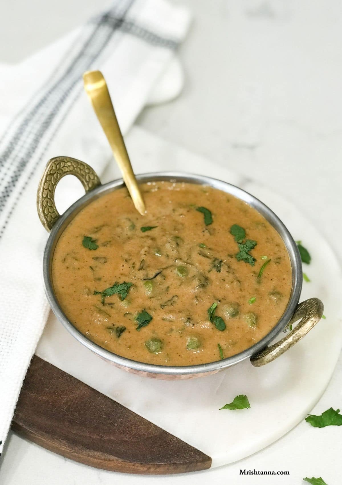 A copper coated bowl is with methi matar malai curry