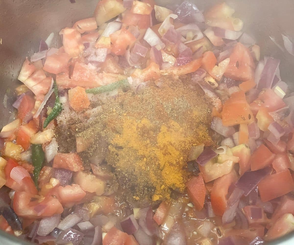 An instant pot has spices, and other ingredients for green gram dal.