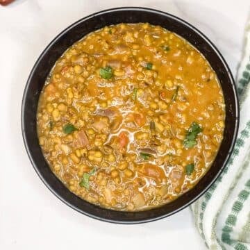 A bowl of green moong dal is on the marble table.
