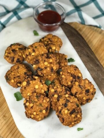 masala vadas are placed on the white serving tray along with sauce