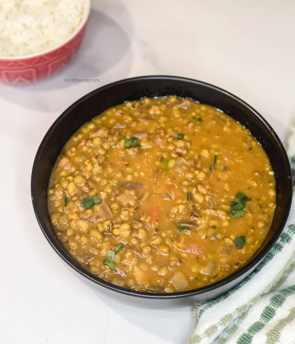 A bowl of instant pot green moong dal is on the marble table.