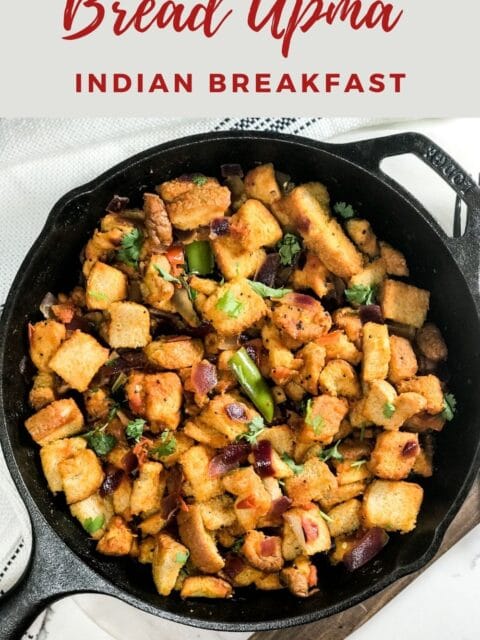 A cast iron pan is filled with bread upma and is on the white surface.