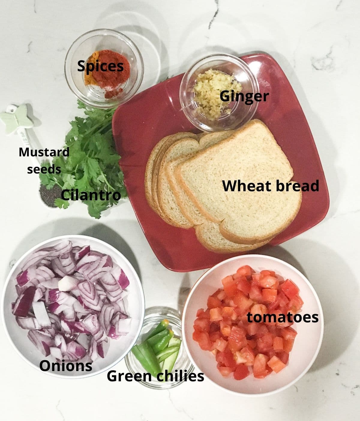 A white surface is filled with bread, chopped onions, tomatoes and green chilies, and spices for bread upma